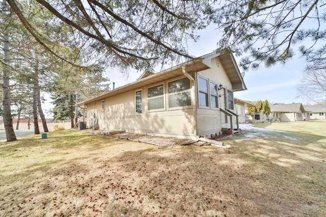 view of side of property featuring a lawn and central AC