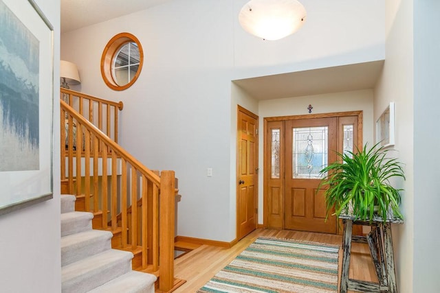 foyer entrance with stairway, wood finished floors, and baseboards