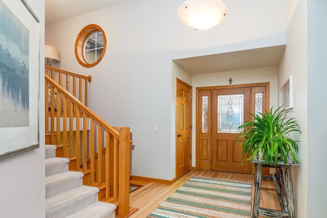 foyer featuring baseboards, stairs, and wood finished floors
