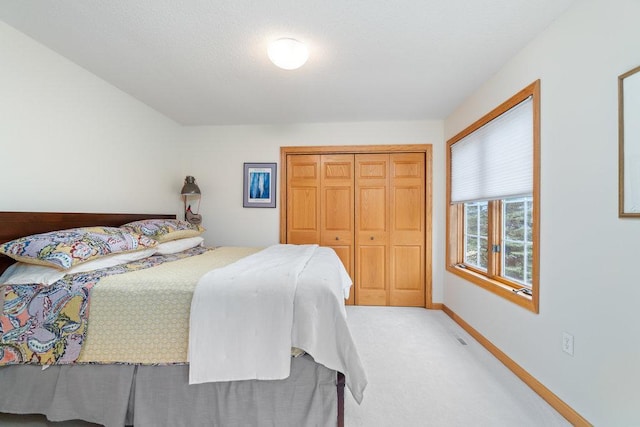 carpeted bedroom featuring baseboards and a closet