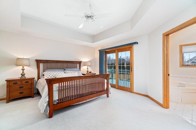 bedroom featuring baseboards, multiple windows, a tray ceiling, and access to exterior