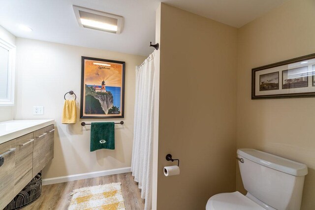 bathroom featuring visible vents, wood finished floors, vanity, baseboards, and toilet