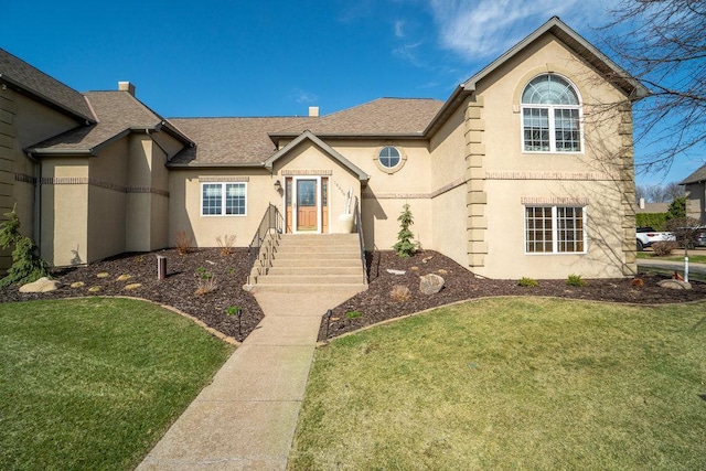 view of front of house featuring a shingled roof, stucco siding, and a front lawn