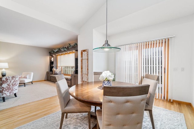 dining space with baseboards, vaulted ceiling, and light wood-type flooring