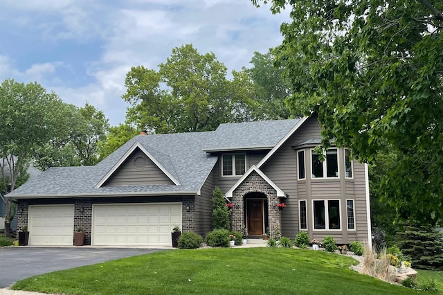 view of front of property featuring a garage, driveway, a shingled roof, a front yard, and brick siding