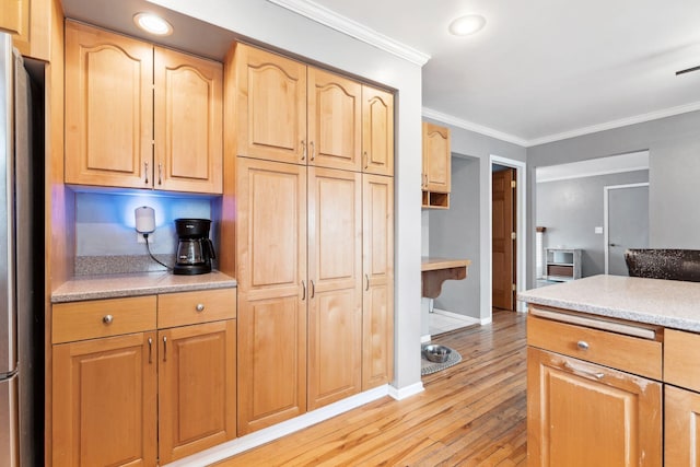 kitchen featuring light wood-style flooring, baseboards, freestanding refrigerator, light brown cabinetry, and crown molding