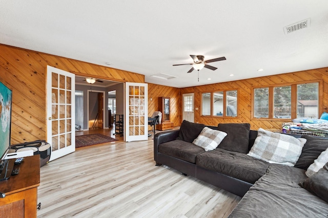 living area featuring wooden walls, recessed lighting, wood finished floors, visible vents, and french doors