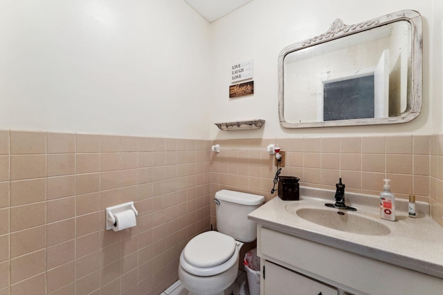 bathroom with tile walls, wainscoting, vanity, and toilet