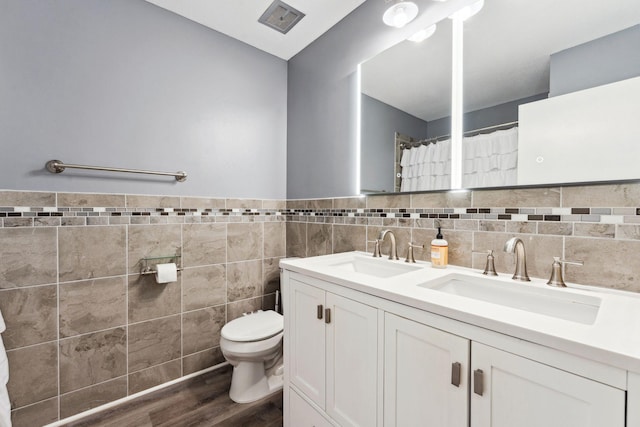 bathroom with toilet, tile walls, a sink, and wood finished floors