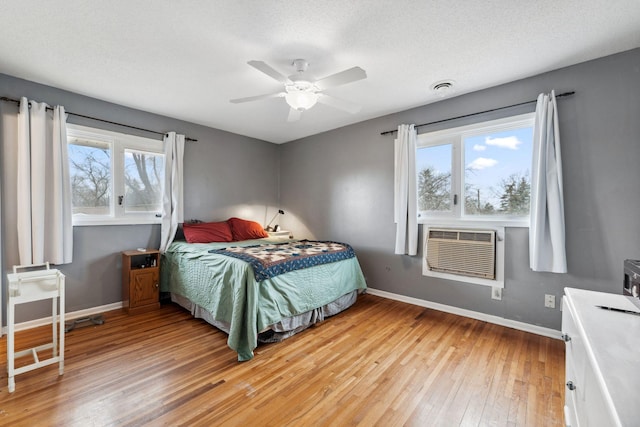 bedroom with light wood finished floors, baseboards, visible vents, and a textured ceiling