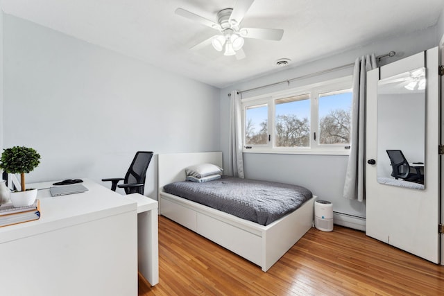 bedroom with light wood finished floors, a baseboard radiator, visible vents, and ceiling fan