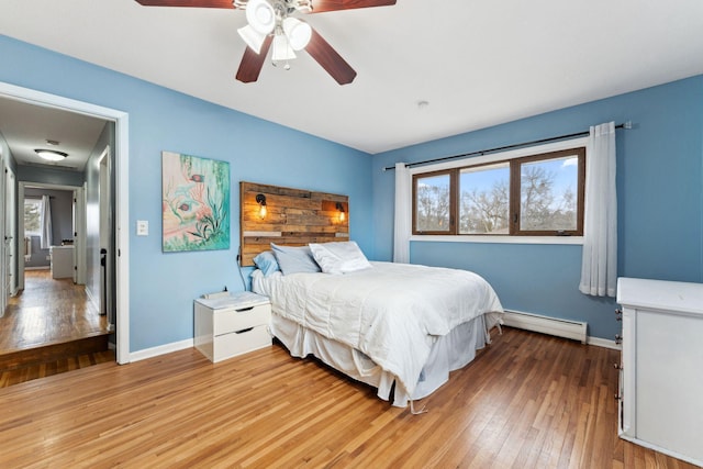 bedroom featuring light wood finished floors, ceiling fan, baseboards, and baseboard heating