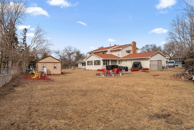 back of property featuring a fenced backyard, a chimney, an outbuilding, a yard, and a patio area