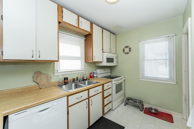 kitchen featuring white appliances, light countertops, a sink, and baseboards