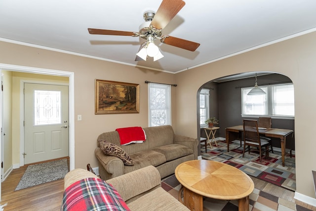 living room with arched walkways, baseboards, wood finished floors, and crown molding