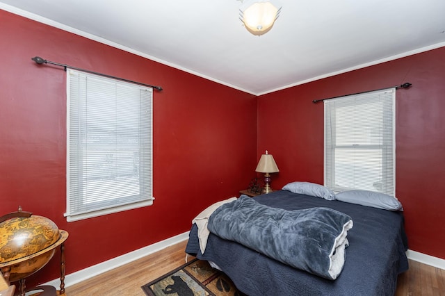 bedroom with crown molding, baseboards, and wood finished floors