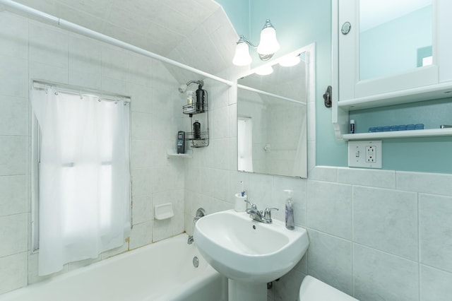 full bath featuring toilet, tile walls, tub / shower combination, and a sink