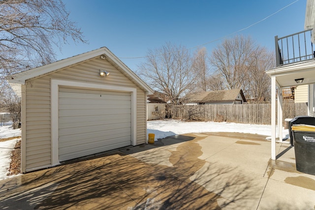 snow covered garage featuring a garage, a storage shed, driveway, and fence