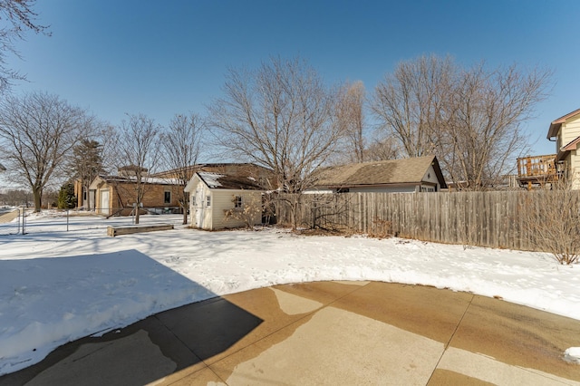 snowy yard featuring a shed, fence, and an outdoor structure