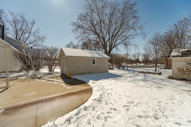 snowy yard featuring an outbuilding and a detached garage