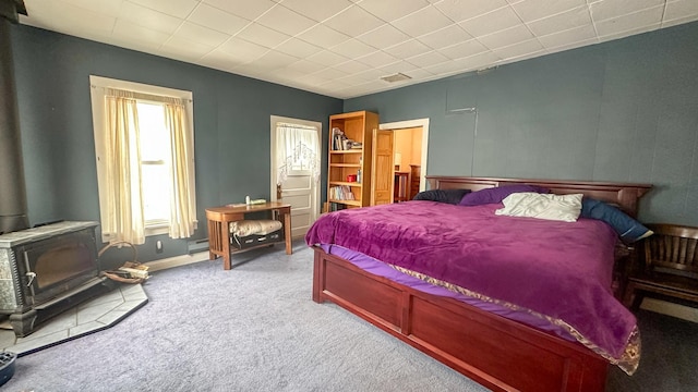 bedroom with visible vents, a wood stove, baseboards, and carpet floors