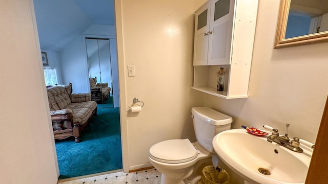 half bath with tile patterned floors, toilet, vaulted ceiling, and a sink