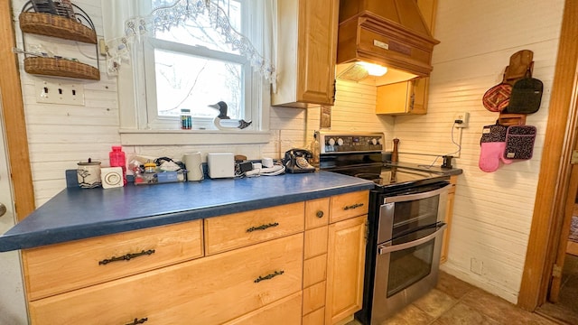 kitchen featuring tile patterned floors, custom range hood, dark countertops, wood walls, and range with two ovens