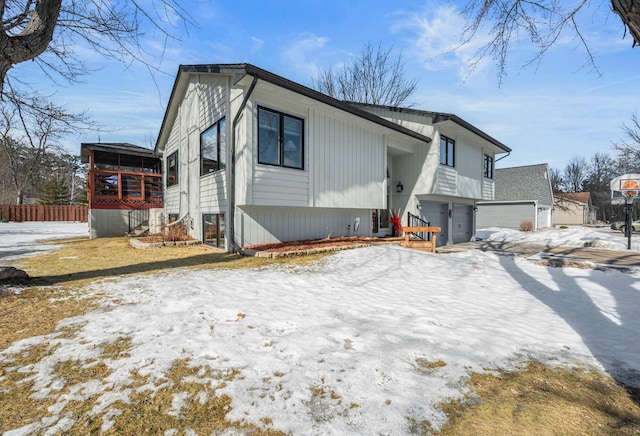 view of front of home with a garage, a sunroom, stairway, and fence