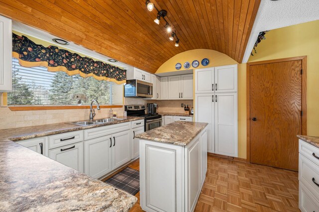 kitchen featuring a sink, a center island, white cabinetry, stainless steel appliances, and lofted ceiling