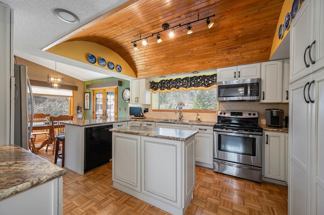 kitchen featuring lofted ceiling, a peninsula, a sink, stainless steel appliances, and white cabinets