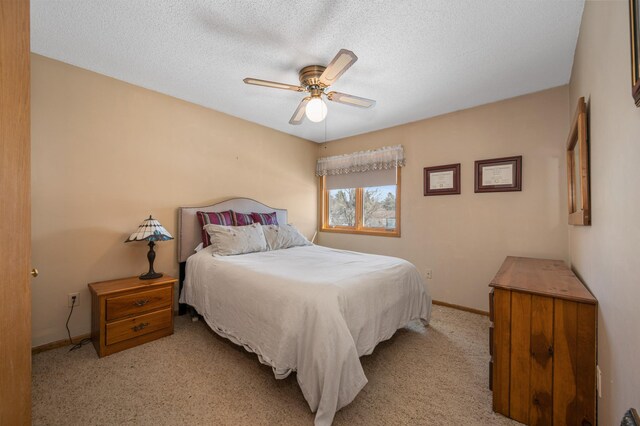 bedroom with light carpet, a textured ceiling, baseboards, and a ceiling fan