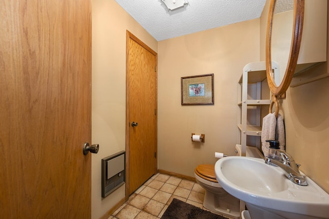 bathroom with baseboards, a sink, a textured ceiling, tile patterned floors, and toilet