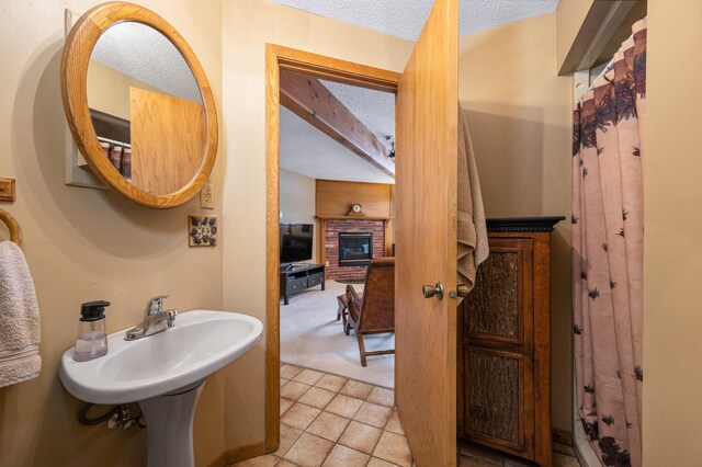 full bathroom with tile patterned flooring, a brick fireplace, and a textured ceiling