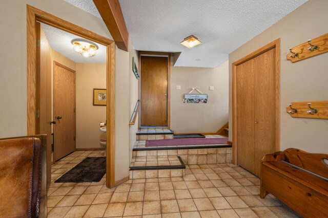 corridor with a textured ceiling, stairs, and baseboards