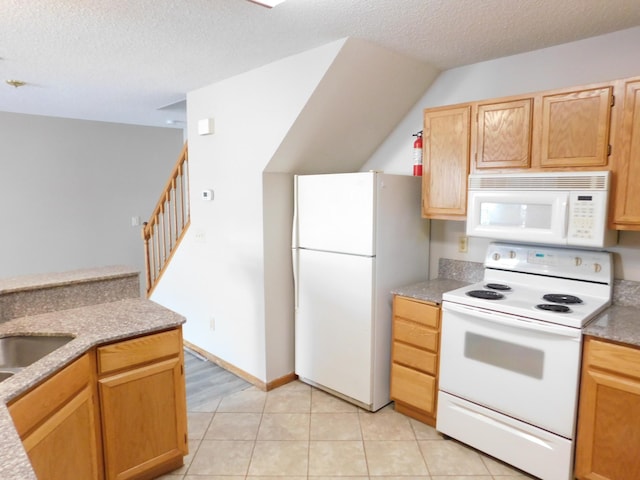 kitchen featuring a textured ceiling, light tile patterned flooring, white appliances, a sink, and baseboards