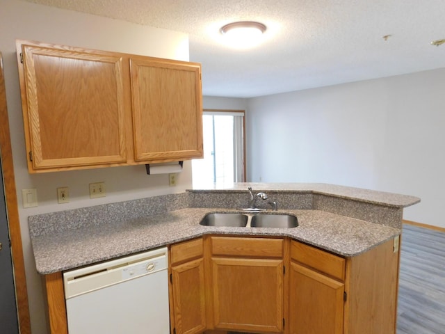 kitchen with white dishwasher, a peninsula, a sink, and a textured ceiling