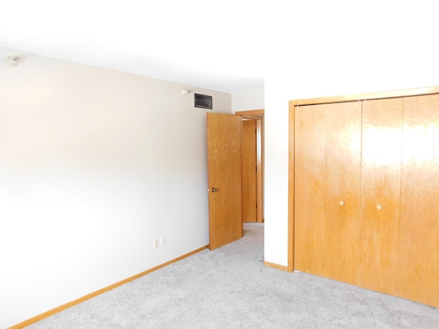 unfurnished bedroom featuring carpet floors, a closet, visible vents, and baseboards