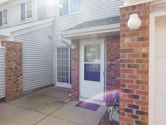 property entrance with brick siding and roof with shingles