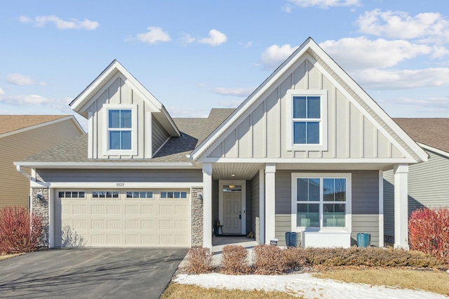 view of front facade with a garage, board and batten siding, driveway, and roof with shingles