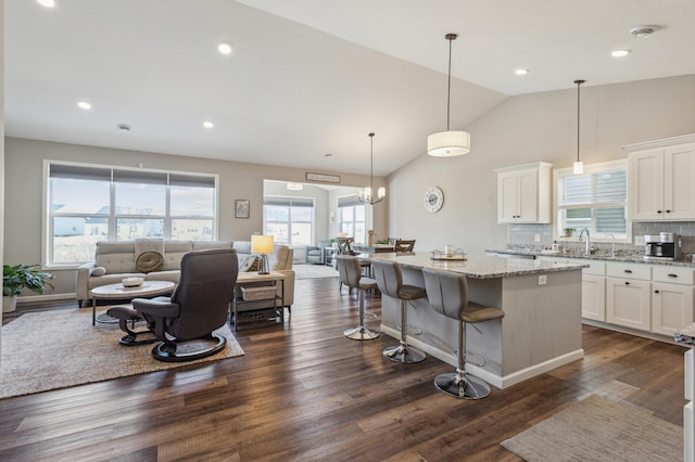 kitchen with light stone counters, dark wood-style floors, white cabinetry, open floor plan, and a center island