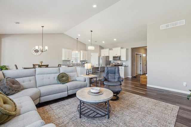 living area with visible vents, baseboards, dark wood-type flooring, and an inviting chandelier