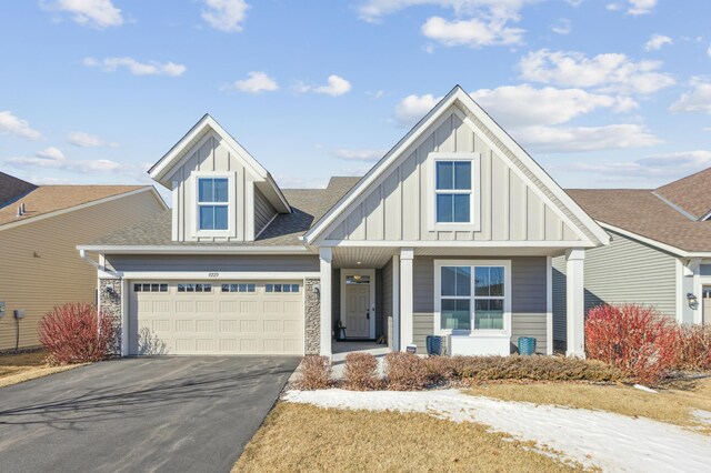 view of front of property with aphalt driveway, board and batten siding, and roof with shingles