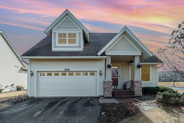 view of front of property featuring a garage, driveway, and a shingled roof