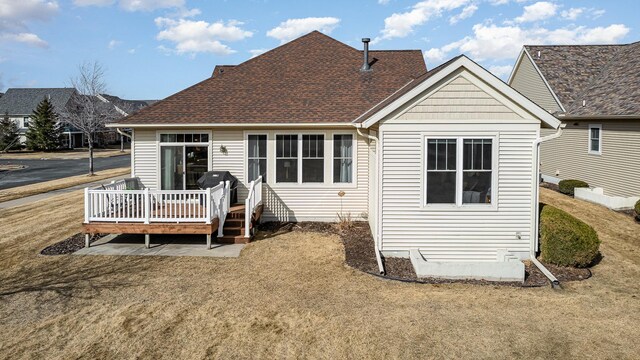 rear view of property with a wooden deck and roof with shingles