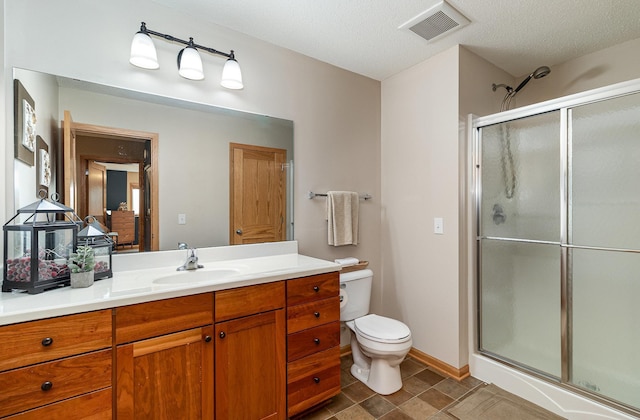 bathroom with vanity, a shower stall, toilet, and visible vents