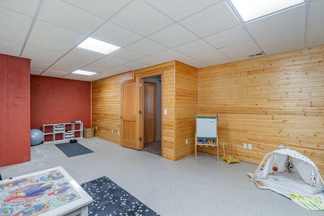 interior space with a paneled ceiling, visible vents, and wood walls