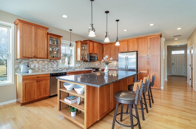 kitchen featuring open shelves, brown cabinetry, appliances with stainless steel finishes, and a center island