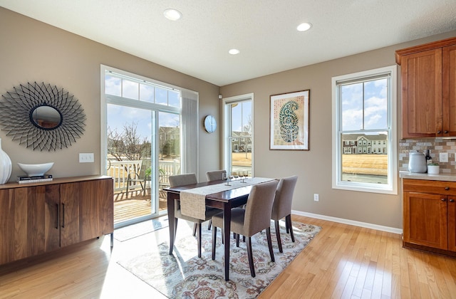 dining space featuring baseboards, light wood-type flooring, and a wealth of natural light