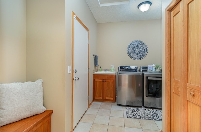 laundry area with light tile patterned flooring, cabinet space, a sink, a textured ceiling, and washer and dryer