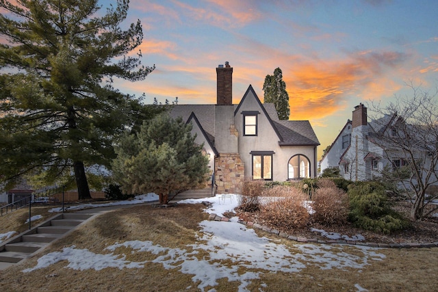 view of front of property featuring stucco siding, stone siding, roof with shingles, and a chimney